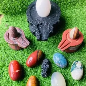 A collection of stones and eggs on a green surface, including a Narmadeshwar shivling from shivansh Narmadeshwar shivling.