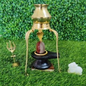 Brass lamp with stone on grass, Narmadeshwar shivling for home shivansh Narmadeshwar shivling.