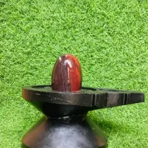 A black and red stone on a black base - Narmadeshwar shivling, available at Shivansh Narmadeshwar shivling, with price.